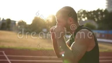 长胡子、精力充沛的拳击手进行拳击运动，在夏季太阳光线照射下站在室外体育场热身